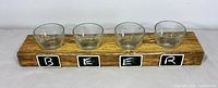 front view wooden board with four glass cups and chalk squares spelling BEER
