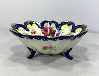 Side view showing scalloped rim, cobalt border, feet, exterior floral sprig