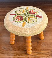 Top view showing floral needlepoint seat and wooden legs