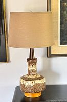 Full view lamp with shade, showing glaze, wood neck, finial, fabric shade.