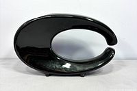 Front view of glossy black C-shaped ceramic vase on small feet