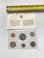 Sealed six-coin set with information card and tape measure for scale