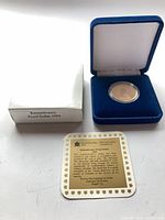 Coin in capsule inside blue velvet case with outer box and certificate displayed