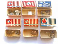 Nine matchboxes with assorted pocket watch parts laid out