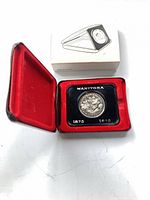 Coin in holder inside red velvet case with outer box visible