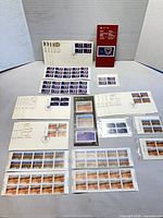 Overview of entire lot showing stamp panes, FDCs, bulletins arranged on table