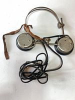 Full view of headphones showing metal band, leather strap, cord