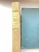 Spine of cloth book beside slipcase showing title label and slipcase wear