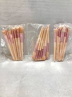 Three sealed makeup brush sets standing side by side in plastic sleeves