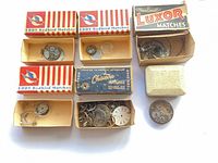 Overview of matchboxes containing watch movements, dials and parts