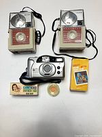 Lot overview showing two Kodak Flashfun cameras, Bell & Howell Big Finder camera, Sylvania flash cubes box, Kodak filter, 126 film box