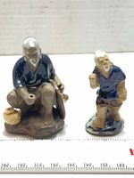 Front view of both porcelain fisherman figurines with scale