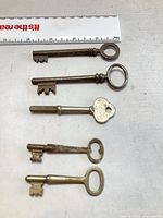All five skeleton keys lined beside ruler