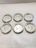 Six coasters top view showing glass starburst centers and metal rims