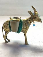 Left profile of brass figurine showing felt saddle, one cup inserted, bead earring