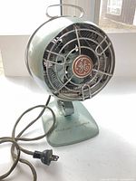Front view showing seafoam fan, chrome cage, GE badge, cloth cord