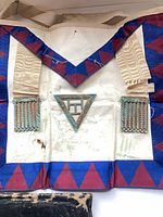 Front view of apron showing border, ribbons, jewel, and waist strap