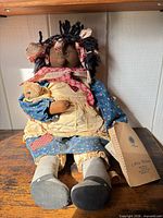 Full view of rag doll seated on wooden surface