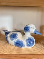 profile view of porcelain duck figurine showing blue spots and beak