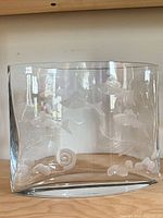 Front view of curved rectangular clear glass vase with etched fish and sea floor details