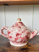 Front view of teapot showing overall form, red speckled finish, lid with knob