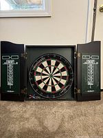 Cabinet open showing dartboard, scoreboards and three darts