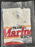 Folded T-shirt in sealed bag showing size XL neck tag and Team Marines Racing text graphic
