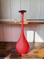 full view of red glass vase on shelf