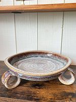 Top view of rustic glazed stoneware footed bowl showing interior swirl and glaze colors