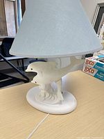 Full view of lamp showing dolphin resin base, fabric shade, power cord, bulb installed