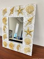 Front view of rectangular seashell-framed mirror