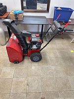 Side view of red Craftsman two-stage snowblower showing chute, engine and wheels