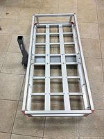 Top view of aluminum cargo carrier showing grid deck, steel receiver tube and red corner caps