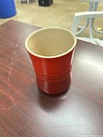 Front view of red stoneware utensil crock showing exterior color and Le Creuset banding