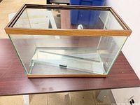 Front angled view of glass aquarium showing wood-look trim and one sliding lid inside