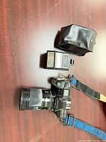 Camera with lens, flash, strap and pouch laid out on table