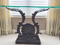 Front view showing cast metal base with shell motif and glass top