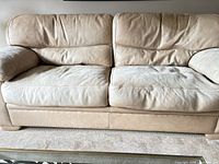 front view of three-seat beige leather sofa showing overall design and wear