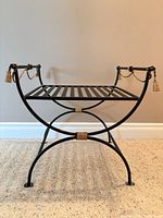 Front angled view of entire bench showing black iron frame, gold rope and tassels