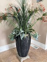 Full view of artificial plant arrangement in black urn on pedestal