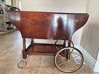 Right side view showing mahogany body, drop leaf down, brass rear wheel and front caster