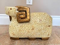 Front view of ceramic ram sculpture showing mosaic finish and gold horns