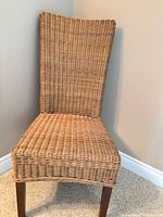 Front view showing wicker seat, high back, wooden legs