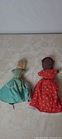 Two cloth topsy-turvy dolls side by side showing one side of each