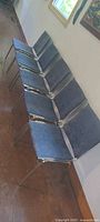 five chrome frame chairs with blue fabric upholstery lined up