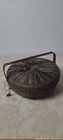 Full view of woven sewing basket with lid and handle