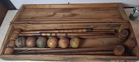 Full view of open wooden case with mallets, balls, stake and wickets