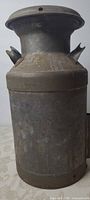 Full front view of the metal milk can showing cylindrical body and neck