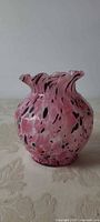 Front view of pink spatter glass vase showing bulbous body and ruffled rim