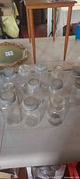 Group of eleven clear glass sealer jars with metal lids on tabletop